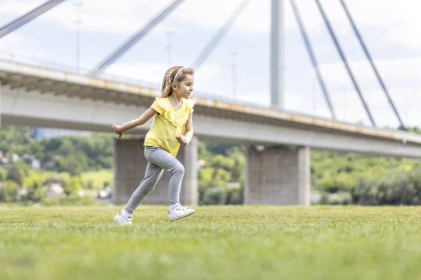 孩子在桥旁的草地上奔跑图片下载