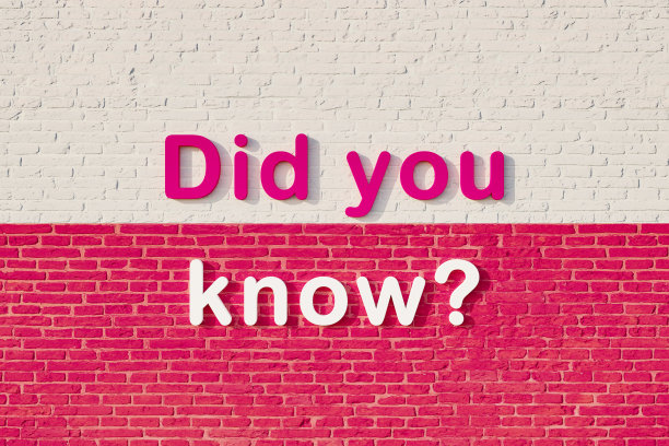 你知道吗?彩色的大写字母靠在白色和紫色的砖墙上。图片下载