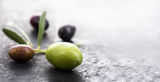 特写新鲜的橄榄水果在黑暗纹理背景与copyspace。图片下载