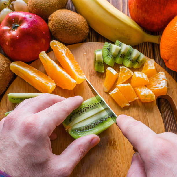 男子在菜板上切水果图片下载