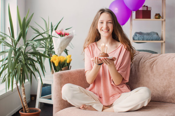 年轻女子拿着蜡烛看着生日蛋糕图片下载