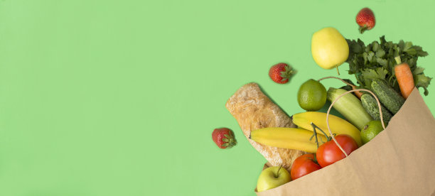 纸袋与蔬菜，水果和法棍在绿色的背景。前视图。副本的空间。图片下载