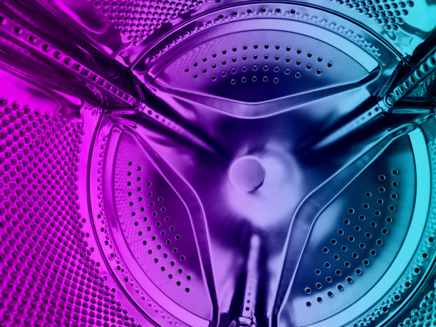 洗衣机滚筒关闭。洗衣机背景。在洗衣机里面。蓝色和粉色调的金属洗衣机滚筒。闪亮的穿孔金属图片下载