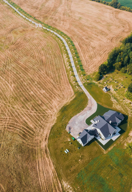 航拍照片，一座两层楼的大房子矗立在农村的一片广阔的草地上图片下载
