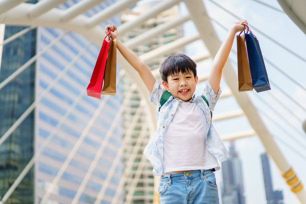 快乐的男孩拿着购物袋。图片下载