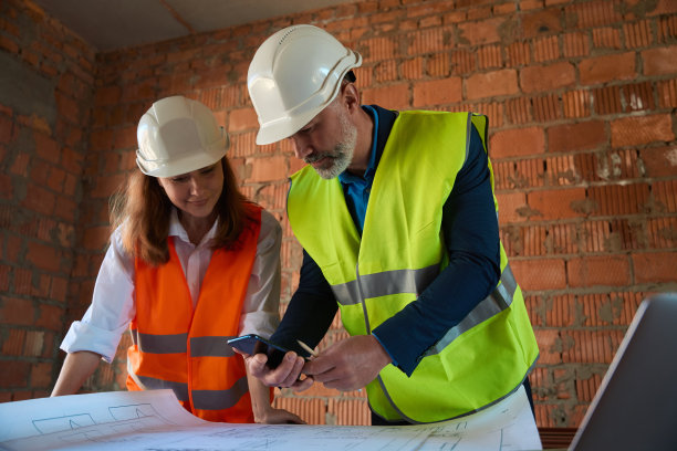 建筑工人讨论建筑工程，看着手机上的3d布局图片下载