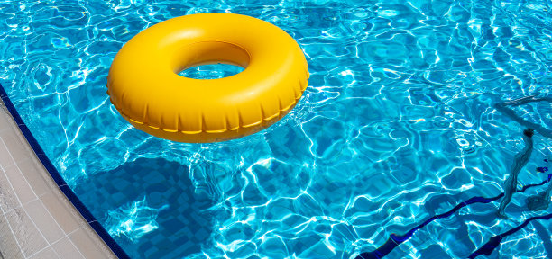 黄色的戒指漂浮在清新的蓝色游泳池图片下载
