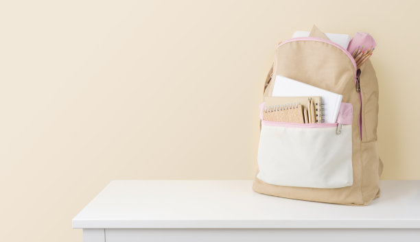 时髦的背包与学校文具在桌子上对米色背景图片下载