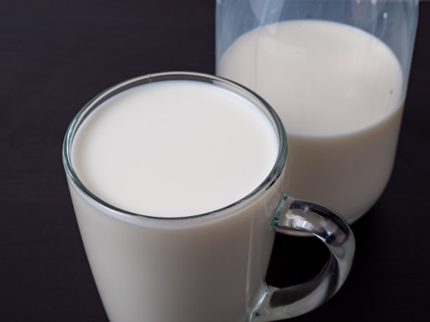 木桌上放着一瓶和一杯牛奶。图片下载