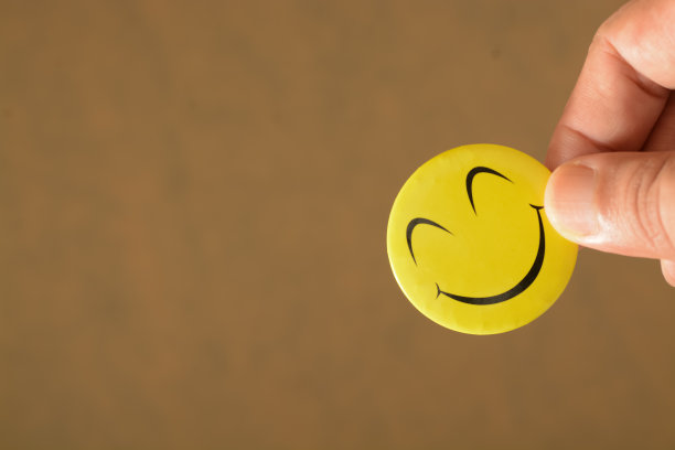 握着笑脸的手象征着积极的心态、建设性的反馈、快乐的生活方式和对健康生活方式的承诺。图片下载