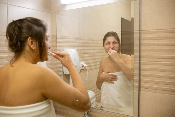 一个年轻女子在浴室里刷牙。图片下载