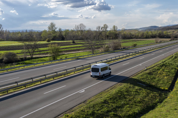 白色现代快递小件货物快递车在高速公路上快速行驶到城市郊区。白色现代舒适的旅游巴士行驶在高速公路上。旅游和旅游车旅游的概念图片下载