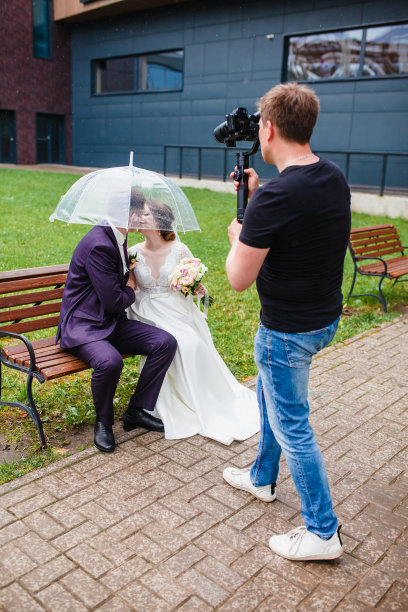 摄像师在长凳上为新婚夫妇拍摄影片图片下载