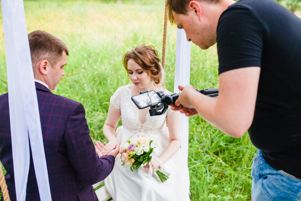 摄像师在松林中拍摄这对新婚夫妇在秋千上的镜头图片下载