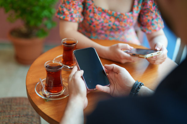 两个人在咖啡馆喝着土耳其茶，玩着手机。图片下载