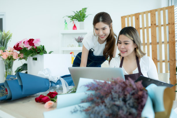 两个亚洲女花商在花店用笔记本电脑工作。图片下载
