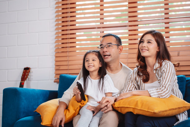 由幸福的父母和女儿在家里客厅的沙发上一起看电视或电影组成的亚洲家庭。享受放松的快乐图片下载