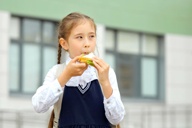 棕色头发的女孩在回家的路上吃着自制的三明治图片下载
