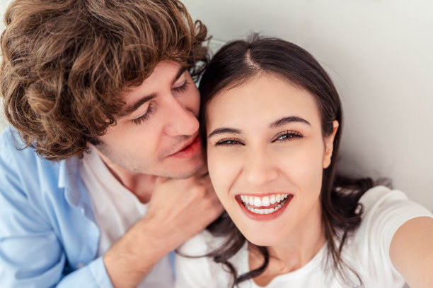 快乐的年轻夫妇在家里休息时微笑自拍，快乐的年轻夫妇在男朋友亲吻女朋友时微笑自拍，男女一起享受约会图片下载