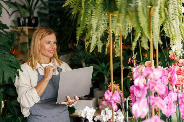 小花店老板，花店老板，穿着围裙，在笔记本电脑上工作，在商店里接受网上订单图片下载
