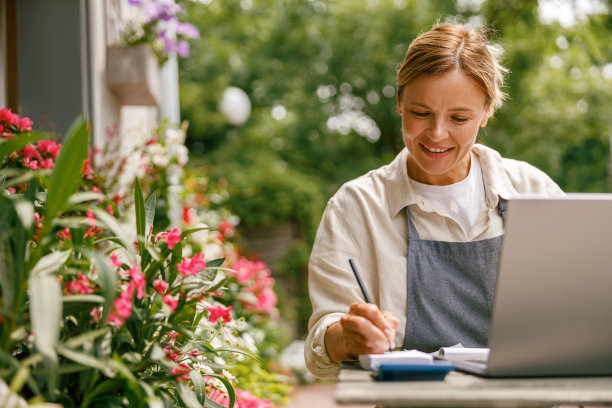 小花店老板，花店老板，穿着围裙，在笔记本电脑上工作，在商店里接受网上订单图片下载