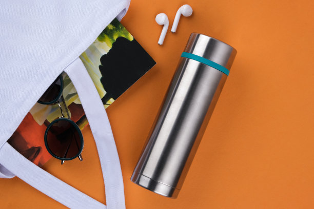İn一个不锈钢热水瓶在橙色的背景。旅行的概念。图片下载