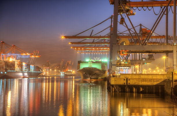 日出时的港口，有船只、货物和五颜六色的灯光图片下载