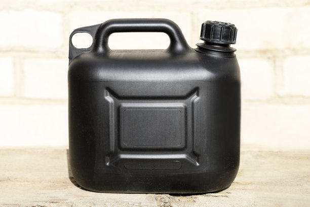 砖墙背景上的黑色塑料汽油罐图片下载