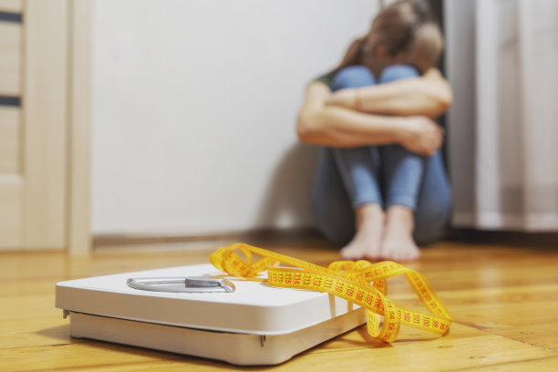 白色的鳞片和沮丧，不安和悲伤的女人用卷尺在木地板上图片下载