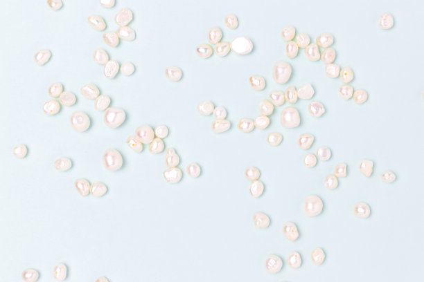 白色的珍珠珠散落在蓝色的背景上。图片下载