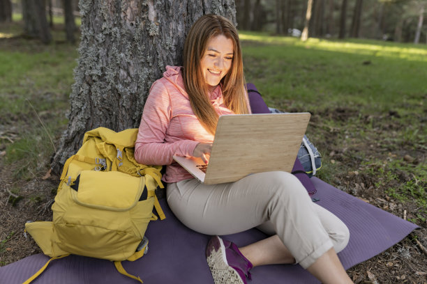 成熟女性露营在大自然远程工作与笔记本电脑图片下载