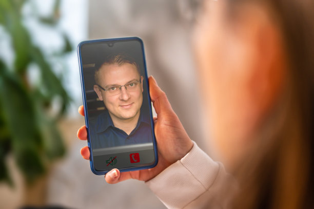 通过智能手机与一位友好的穿蓝色衬衫的男士进行视频通话图片下载