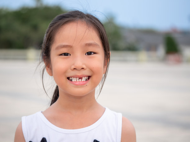 近距离拍摄亚洲儿童可爱或儿童女孩微笑的眼睛，白色的牙齿和一个破碎的牙齿或从婴儿或乳牙脱落在7岁图片下载