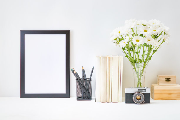 黑色框架，书，花瓶里的白花，浅色背景上的办公用品。空的海报框架模型演示设计，文字，字母图片下载