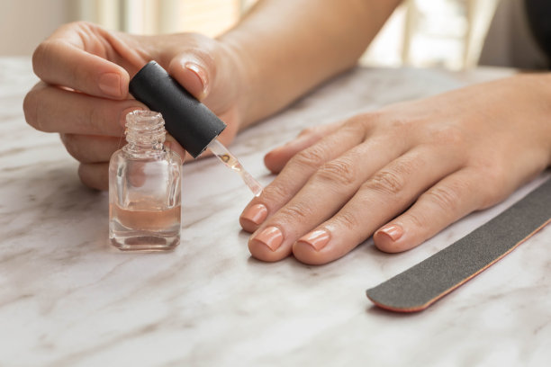 用自然的颜色修指甲，在锉刀旁涂指甲油，在美容院的桌子上，个人护理和卫生图片下载
