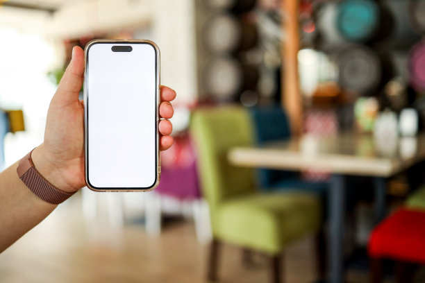 这个女孩手里拿着一个手机，屏幕上是一个空白的孤立屏幕，背景是餐馆里的食物。放菜单或评论的地方图片下载