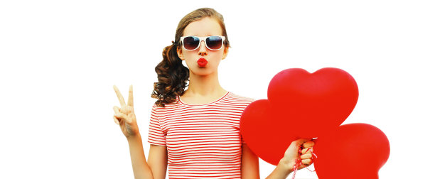 美丽的年轻女子的肖像与红色的心形状的气球吹她的嘴唇发送甜蜜的空气吻戴墨镜孤立在白色背景图片下载