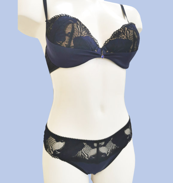 时髦的内衣在一个女性人体模型上隔离在蓝色的背景。美丽的花边蓝色与黑色内衣套装-胸罩和内裤。图片下载