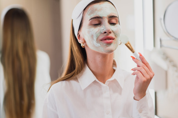 迷人的年轻女子应用她的新保湿面膜库存照片图片下载