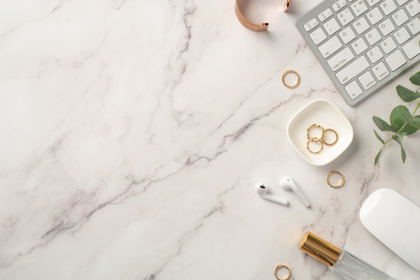 经营理念。俯视图照片的工作站键盘，电脑，鼠标，无线耳机，金戒指，手镯，香水瓶和桉树在白色大理石背景与copyspace图片下载