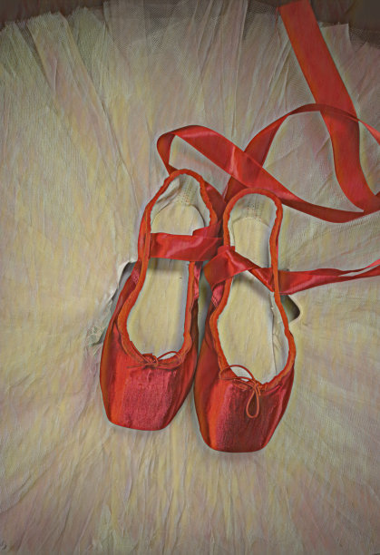 红色芭蕾尖头鞋放在黑色芭蕾舞裙上。图片下载