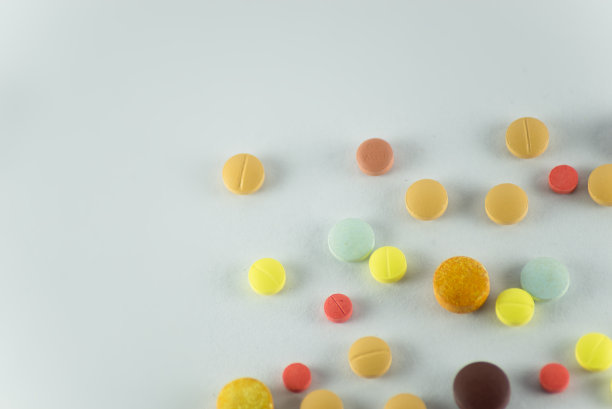几个不同颜色的药片，有些是旧的，放在浅灰色的表面上。图片下载
