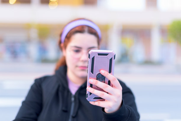 一个年轻的成年女孩拿着她的手机与一个粉红色的箱子，而聊天的特写图片下载