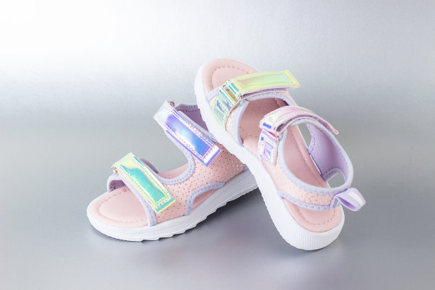 时髦的全息凉鞋为孩子在灰色的背景。闪亮的时尚夏季鞋图片下载