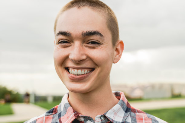 快乐的年轻秃头女人看相机户外-真实和真实的人的概念图片下载