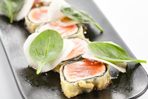 三文鱼卷烧——烤三文鱼。切成薄片的生鱼片。三文鱼塔烧配上美味的柑橘柚子塔烧酱。日本海鲜在黑色盘子孤立在白色背景。图片下载