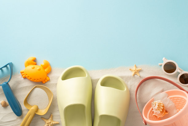 与海边的孩子们一起踏上梦幻般的海滩假期:鸟瞰图展示沙堡套件，拖鞋，太阳镜和海星在孤立的蓝色背景与广告或文字的文案空间图片下载