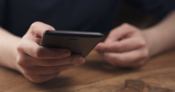 年轻的女青少年手握智能手机坐在桌子旁的特写图片下载