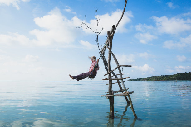坐在沙滩上的木制秋千上的女人图片下载