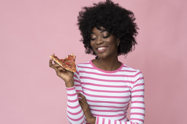 非裔美国妇女拿着一块披萨。图片下载
